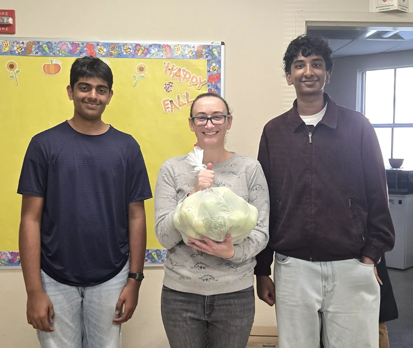 Bin to Better volunteers handing a teacher a bag of repurposed tennis balls for her classroom