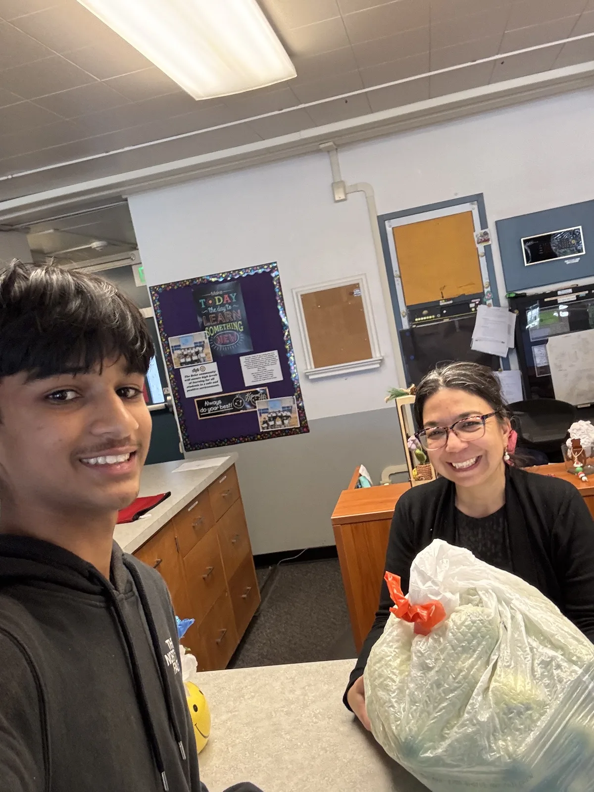 A volunteer and a teacher with a bag of tennis balls delivered to her classroom