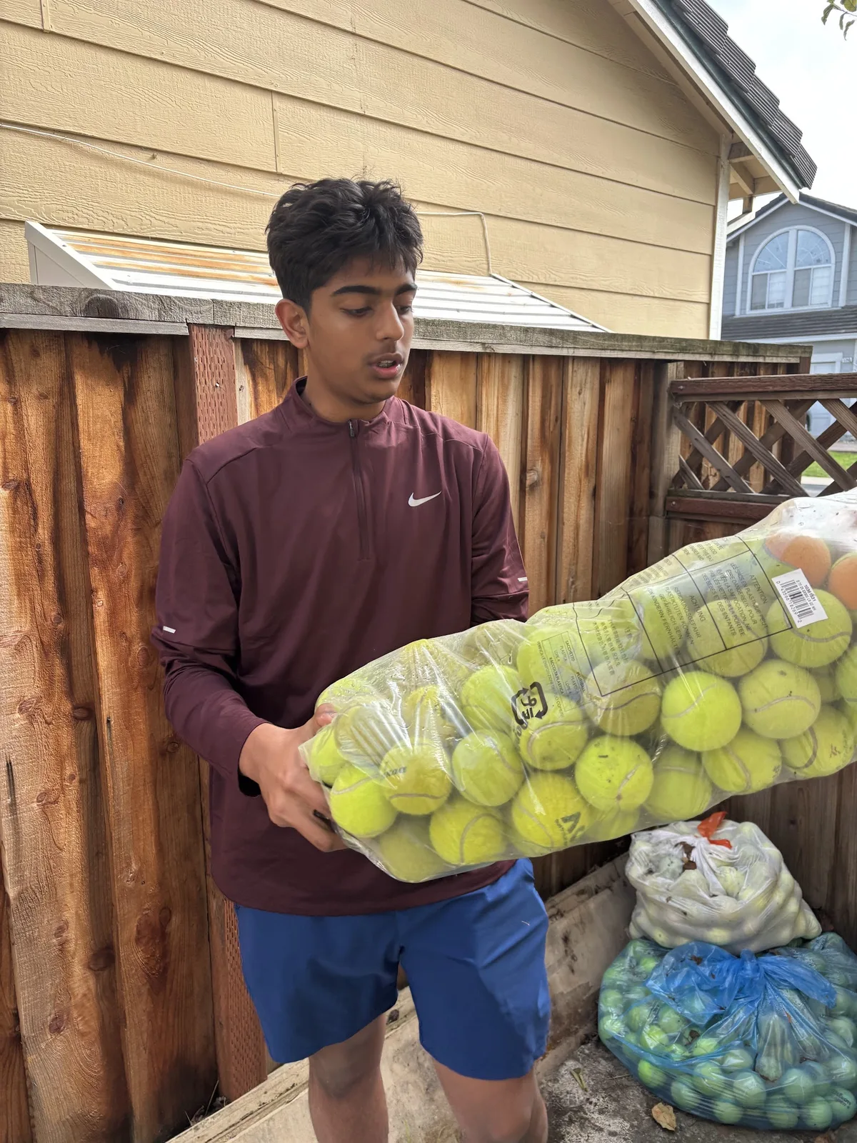 A volunteer holding a bag of collected tennis balls before an animal shelter drop-off