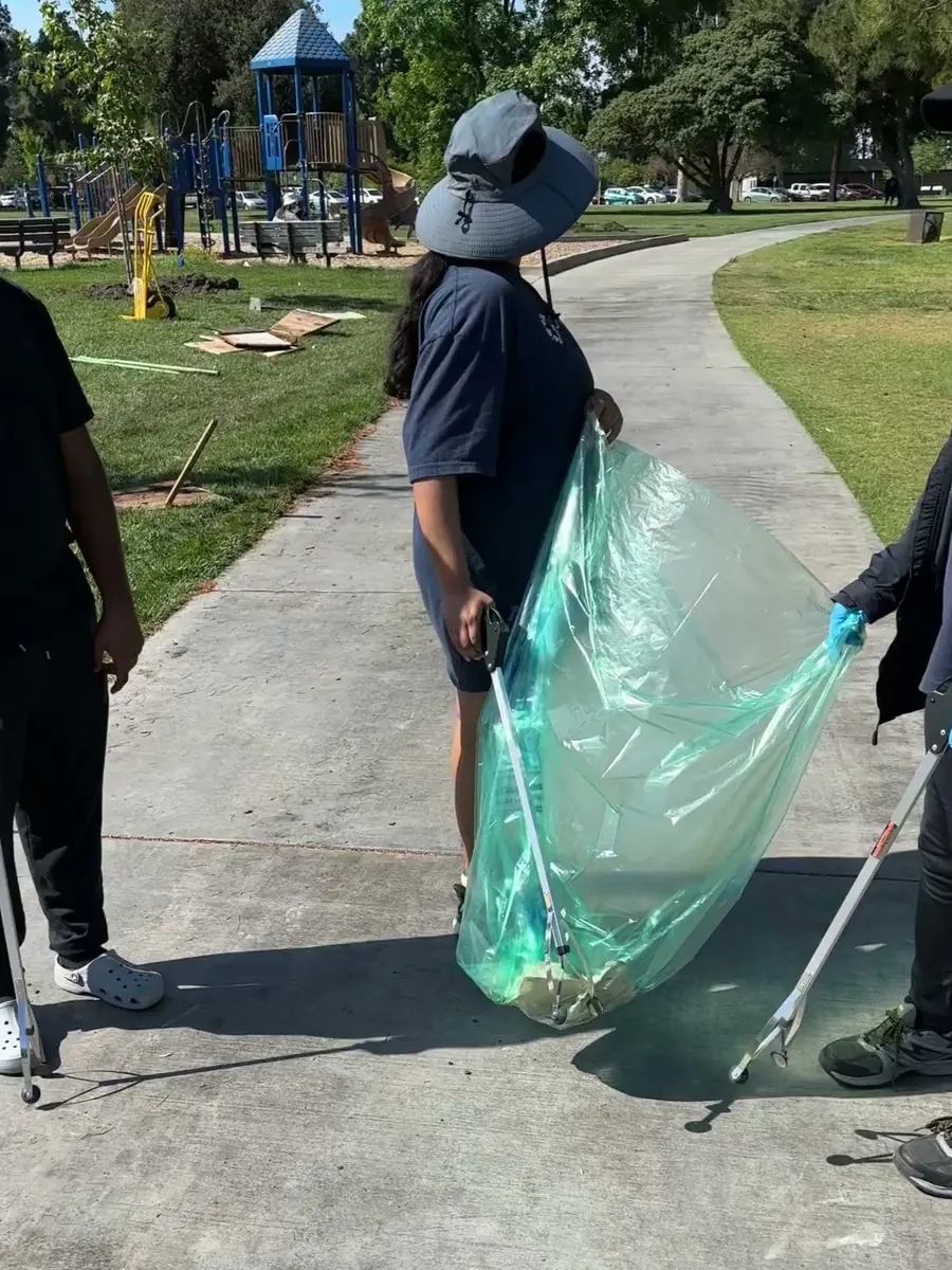 A volunteer carrying a full bag of collected litter down the path