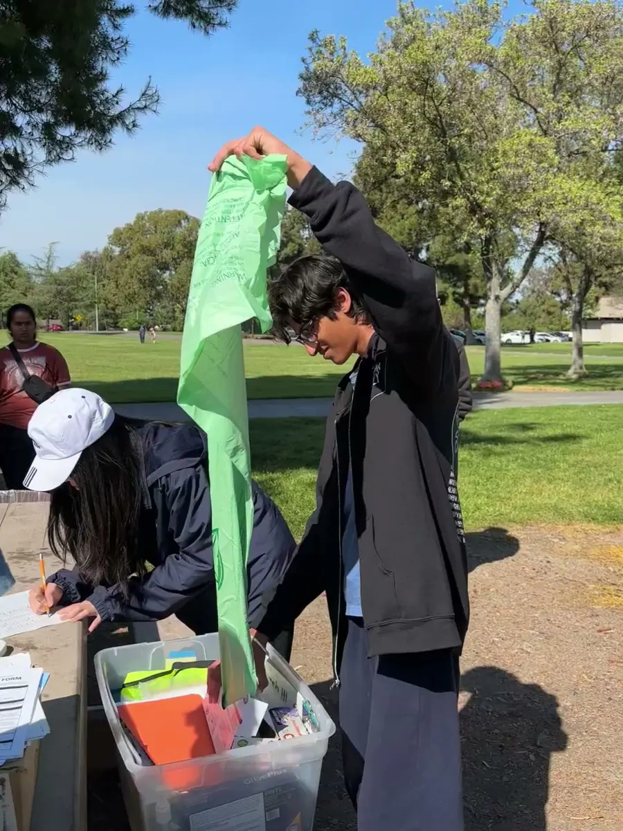 A volunteer handing out trash bags from the supply bin