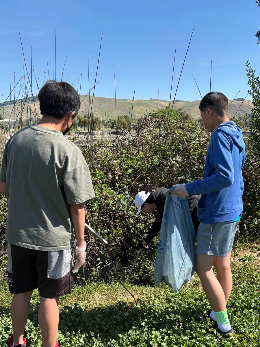 Volunteers clearing trash from bushes beside the trail