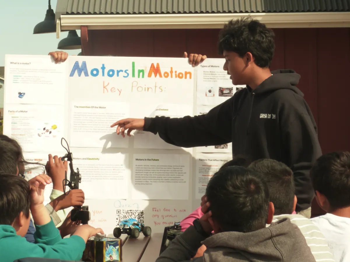 An instructor walking students through the Motors in Motion poster
